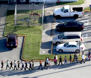 Students are evacuated by police from Marjory Stoneman Douglas High School in Parkland, Fla.