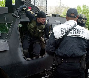 Whitman County Sheriff Deputy Chris Chapman climbs out of the Whitman County Washington Regional SWAT Team armored vehicle outside the Moscow Police Department in Moscow, Idaho, Sunday, May 20, 2007.