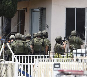 San Diego Police SWAT officers break out windows as they enter a house with a possible suspect inside Friday, July 29, 2016 in San Diego. (AP Photo/Denis Poroy)