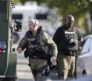 Police don body armor as authorities negotiate with two men who are barricaded in a home and holding a woman and five children hostage in the south suburb of Harvey, Ill., Tuesday, Aug. 19, 2014, south of Chicago. (AP Image)