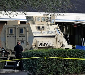 A Sebring, Fla., police officer stands near a Highlands County Sheriff's SWAT vehicle that is stationed in front of a SunTrust Bank branch, Wednesday, Jan. 23, 2019, in Sebring, Fla.