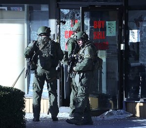 Police officers in SWAT gear enter a pawn shop Thursday, Oct. 5, 2017, in Roswell, Ga., as they search for a burglary suspect.