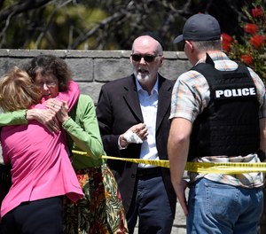 Two people hug as another talks to a San Diego County Sheriff's deputy outside of the Chabad of Poway Synagogue Saturday, April 27, 2019, in Poway, Calif.