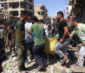 Syrians carry a victim after twin bombings struck Kurdish town of Qamishli, Syria, Wednesday, July 27, 2016.