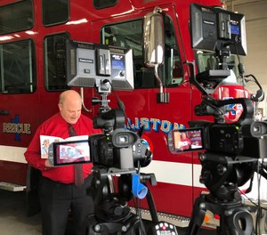 Holliston Fire Department Chief Michael Cassidy reads a children's book in the apparatus bay for the cameras.