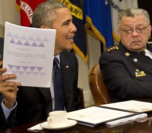 Philadelphia Police Commissioner Charles Ramsey watches as President Obama holds up a copy of the interim report of the President's Task Force on 21st Century Policing, Monday, March 2, 2015.