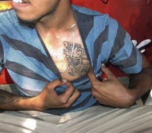 In this Sept. 5, 2014 photo, a reputed member of the Los Solidos street gang shows his tattoo to police in Hartford, Conn.