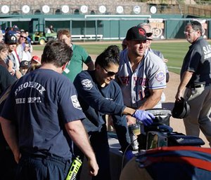 Scottsdale Scorpions outfielder Tim Tebow, center, comforts a fan, on ground, who was suffering a seizure, following Tebow's debut against the Glendale Desert Dogs in a baseball game Tuesday, Oct. 11, 2016, during the Arizona Fall League in Glendale, Ariz.