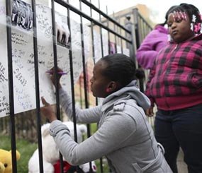 In this April 30, 2014 photo, family and friends of 14-year-old Endia Martin sign posters at a makeshift memorial during a vigil for the girl who was shot and killed April 28 in Chicago allegedly by another 14-year-old girl in a dispute concerning a boy. (AP Image)