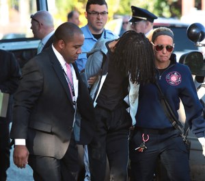 A handcuffed teen is taken to an ambulance after police officers caught him in a crashed Honda SUV that hit a building after being chased by police at Allen and South Jefferson avenues on Monday, Oct. 29, 2018. The SUV was wanted in connection with the robbery and shooting of a retired officer, who later died at a hospital. (Robert Cohen/St. Louis Post-Dispatch/TNS)