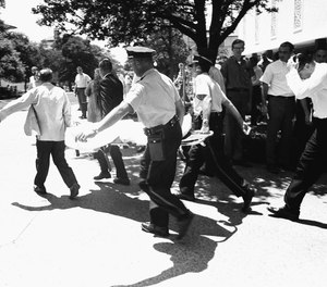 In this Aug. 1, 1966, file photo, one of the victims of Charles Whitman, the sniper who gunned down victims from a perch in the University of Texas tower, is carried across the campus to a waiting ambulance in Austin.