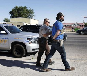 Protester Wyatt Winn is led away in handcuffs outside Big Daddy Zane's bar Monday, May 4, 2020, near Odessa, Texas. Winn was one of several people who showed up to support the bar's owner in her decision to open and serve customers.