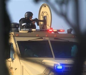 A Hidalgo County Sheriff points a rifle from the top of an armored vehicle Tuesday during a standoff with a capitol murder suspect in La Joya, Texas on Tuesday, July 22, 2014. (AP Image)