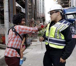 Jasen Frelot, left, holding his daughter Ruby, gives a pat to Seattle police officer Daniel Aguirre after handing the officer a rose in response to the shootings of police officers in Dallas, Friday, July 8, 2016, in Seattle. (AP Image)
