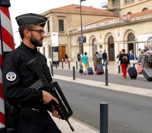 A police officer stands guard while passengers enter the Marseille Saint Charles train station, a day after a man fatally stabbed two women outside the train station, in Marseille, southern France, Monday, Oct. 2, 2017.