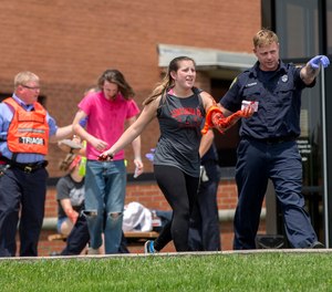 In a May 25, 2016 file photo, an emergency worker directs a volunteer with simulated injuries during a training exercise for an active shooter at Hopewell Elementary School, in West Chester, Ohio.