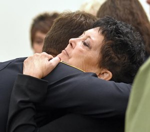 In this Sept. 8, 2016 file photo Julie Benner, widow of police officer Gregg "Nigel" Benner, is given support by members of the Rio Rancho Police Department in a Los Lunas, N.M., courtroom on the first day of testimony in the trial of Andrew Romero for the shooting death of Benner. (AP File Photo/The Albuquerque Journal)