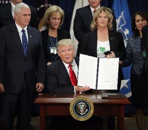 United States President Donald Trump (C) displays one of the four executive orders he signed during a visit to the Department of Homeland Security January 25, 2017 in Washington, DC.