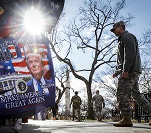 Military personnel walk along the National Mall in Washington, Wednesday, Jan. 18, 2017, alongside vendors selling President-elect Donald Trump merchandise ahead of Friday's presidential inauguration.