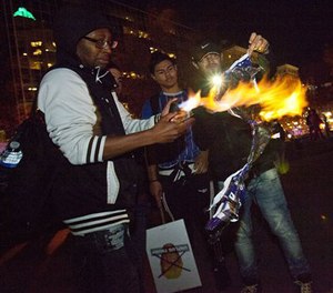 Protesters try to burn a Donald Trump sign as they gather at Rosa Parks Circle in Grand Rapids, Mich., Thursday, Nov. 10, 2016, in opposition of Trump's presidential election victory.