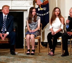 From left, President Donald Trump, Marjory Stoneman Douglas High School student students Carson Abt, and Ariana Klein, listen as Carson's father Frederick Abt, speaks during a listening session with high school students, teachers, and others in the State Dining Room of the White House in Washington, Wednesday, Feb. 21, 2018.