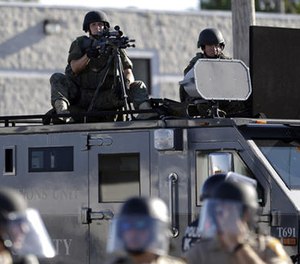 In this Aug. 9, 2014 file photo, a police tactical team moves in to disperse a group of protesters in Ferguson, Mo. that was sparked after Michael Brown, an unarmed black man was shot and killed by Darren Wilson, a white Ferguson police officer.