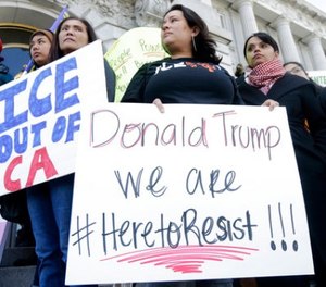 In this Jan. 25, 2017 file photo protesters hold signs as they listen to speakers at a rally outside of City Hall in San Francisco, Calif. California Gov. Jerry Brown signed legislation, SB54, the statuary state bill, that extends protections statewide for immigrants living the United State illegally, Thursday, Oct. 5, 2017. (AP Photo/Jeff Chiu)