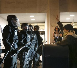 Police stand in front of people who march through downtown Portland, Ore., to protest of the election of president-elect, Donald Trump, Friday, Nov. 11, 2016.
