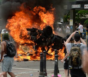 A police car burns during a protest that turned violent on May 30. Prosecutors charged an eighth person on Monday for the burning. (Photo/TNS)