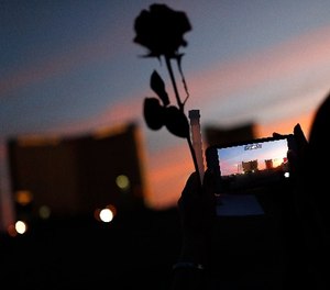 A woman takes a picture of the Mandalay Bay hotel and casino during a vigil for victims and survivors of the mass shooting in Las Vegas, Sunday, April 1, 2018, in Las Vegas. (AP Photo/John Locher)