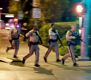 In this Oct. 1, 2017, file photo, police run toward the scene of a mass shooting near the Mandalay Bay resort and casino on the Las Vegas Strip in Las Vegas.