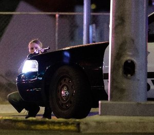 A police officer takes cover behind a police vehicle during a shooting near the Mandalay Bay resort and casino on the Las Vegas Strip, Sunday, Oct. 1, 2017, in Las Vegas.