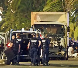 Police stand by as medical personnel attend a person on the ground, right, in the early hours of Friday, July 14, 2016, on the Promenade des Anglais in Nice, southern France, next to the lorry that had been driven into crowds of revelers late Thursday.