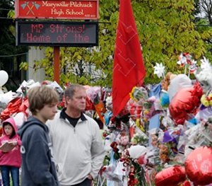 Gay Soriano, left, talking with daughter Gabby, 11, as her brother Titan, 13, and father Rick walk nearby and along a memorial for victims of a deadly school shooting nearly a week earlier, in Marysville, Wash.