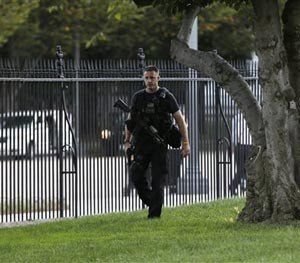 A member of security with a weapon walks along the interior of the perimeter fence on White House North Lawn along Pennsylvania Avenue in Washington, Monday, Sept. 22, 2014.