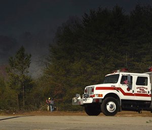 Volunteer firefighters Sheri Torbett and Jeannie Vaughn, left, with the Sequoyah Volunteer Fire Department, use leaf blowers remove debris off the break near the Mowbray Volunteer Fire Hall in Soddy-Daisy, Tenn. (Tim Barber /Chattanooga Times Free Press via AP)