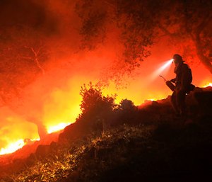 A San Diego Cal Fire firefighter monitors a flare up on a the head of a wildfire.