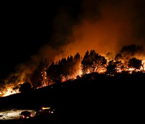 Firefighters watch from their fire trucks as wildfires continue to burn near Calistoga, Calif.
