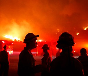 Firefighters gather in front of a residential area as a wildfire burns along the 101 Freeway.