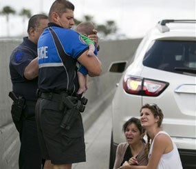 Sweetwater officer Amauris Bastidas helps rescue a five-month-old baby boy, Sebastian de la Cruz, who stopped breathing. (AP Image)