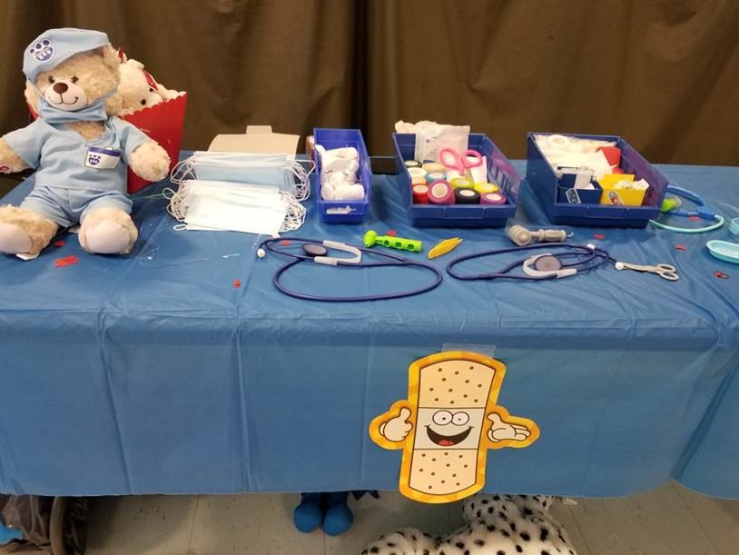 The event included three first aid tables where children practiced procedures on teddy bears.