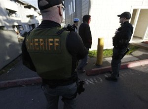 Snohomish County Sheriff's deputy Bud McCurry, left, and Mike Woodruff, a Washington Dept. of Corrections officer who works with the Snohomish County Sheriff's Dept. gang unit, talk to young people walking through an apartment complex, as they patrol the area Thursday, Feb. 18, 2010, in Everett, Wash.