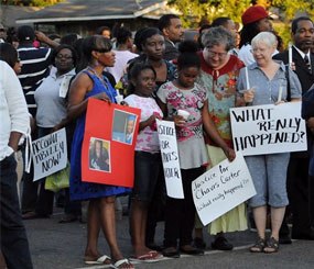 In this Aug. 6, 2012 file photo, supporters of Chavis Carter hold signs during a candlelight vigil at the First Baptist Church in Jonesboro, Ark. An autopsy report released Monday, Aug. 20, lists Carter's death as a suicide.