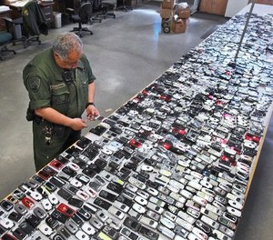 In this April 10, 2009, file photo, Correctional Officer Jose Sandoval inspects one of the more than 2,000 cell phones confiscated from inmates at California State Prison, Solano in Vacaville, Calif. (AP Photo/Rich Pedroncelli, File)