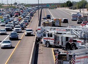 The westbound land is closed and the eastbound lane is backed up as fire and police crews work to remove the driver from a wrecked police transport, Wednesday, Sept. 23, 2015, in Mesa, Ariz. (AP Photo/Matt York)