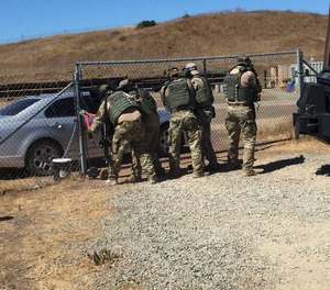 Tactical officers breach a gate at the start of a training exercise.
