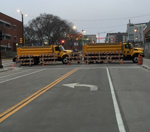 Two municipal vehicles are used to block access to the start/finish area of a marathon.