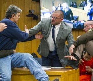 Randall Margraves, father of three victims of Larry Nassar , left, lunges at Nassar, bottom right, Friday, Feb. 2, 2018, in Eaton County Circuit Court in Charlotte, Mich. (Cory Morse/The Grand Rapids Press via AP)