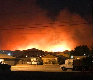 Flames from a wildfire loom up over a neighborhood in Santa Paula, Calif.