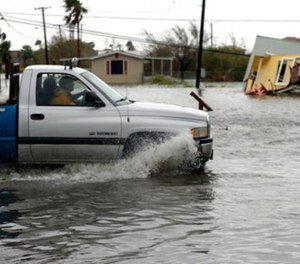 A truck in flood waters passes a home damaged in the wake of Hurricane Harvey, Saturday, Aug. 26, 2017, in Aransas Pass, Texas.